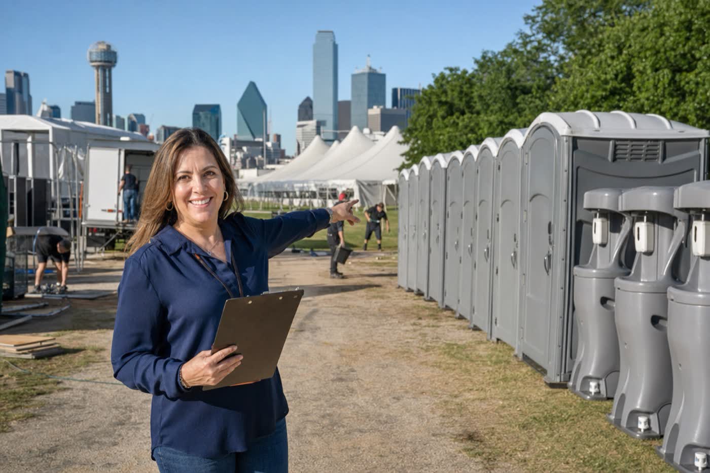 An event planner with a clipboard pointing to rows of portable toilets and hand-wash stations at a Dallas festival setup